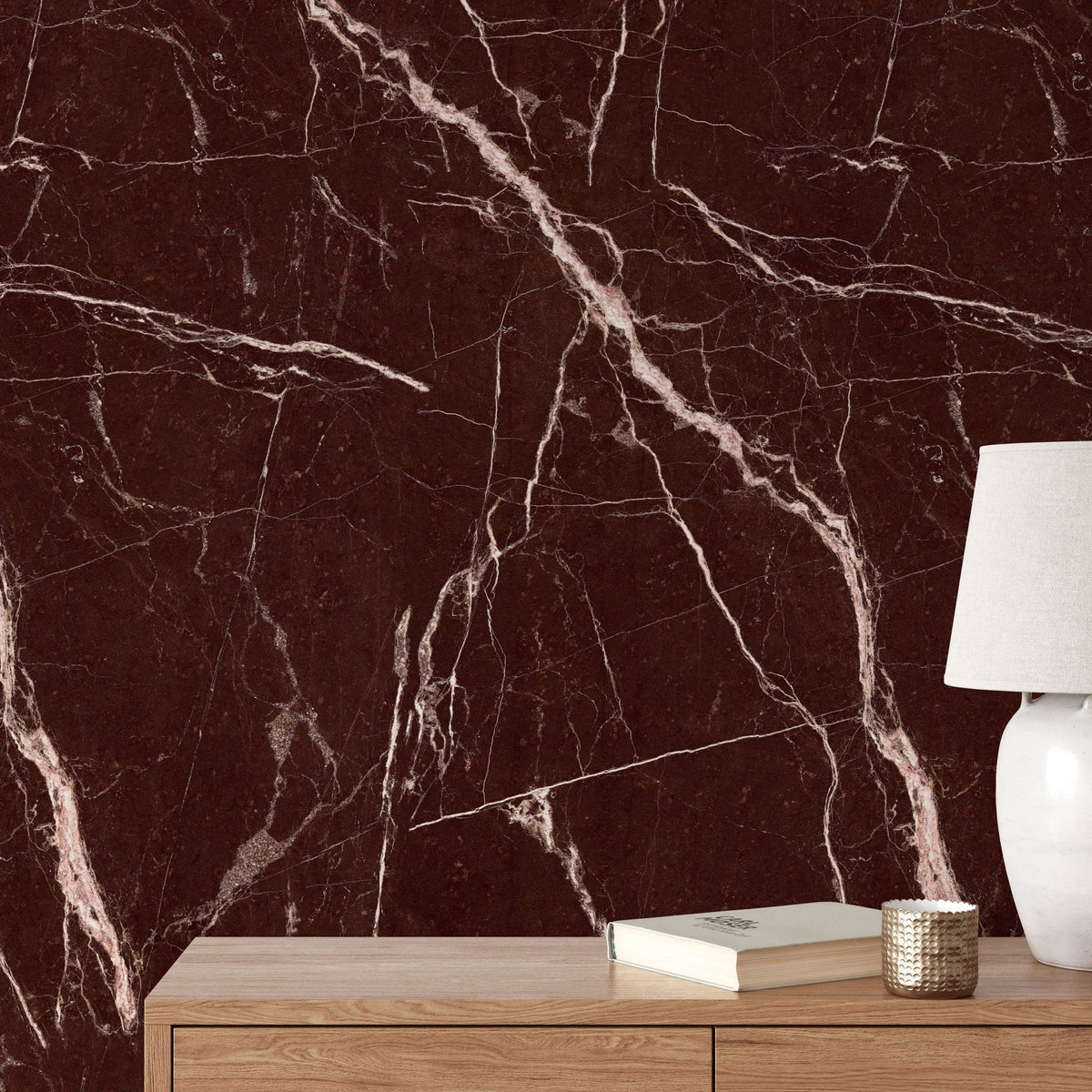 Red marble wallpaper behind a wooden console with a table lamp