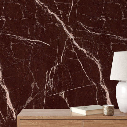 Red marble wallpaper behind a wooden console with a table lamp